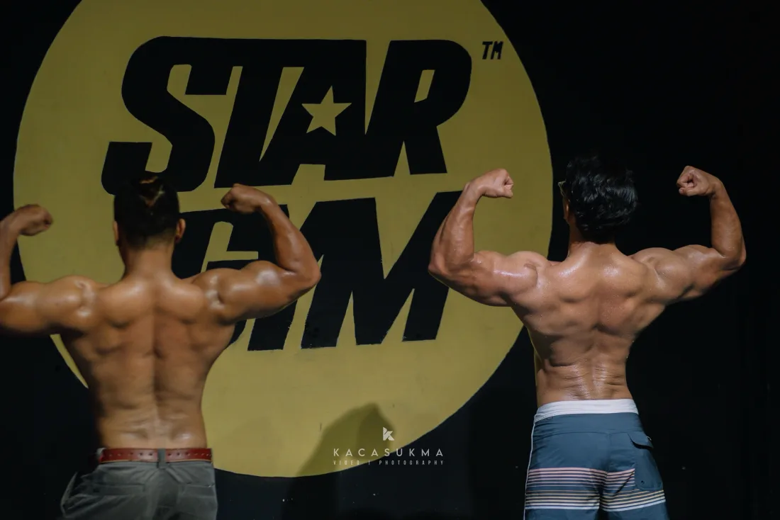 Two athletes performing a back double biceps pose on stage