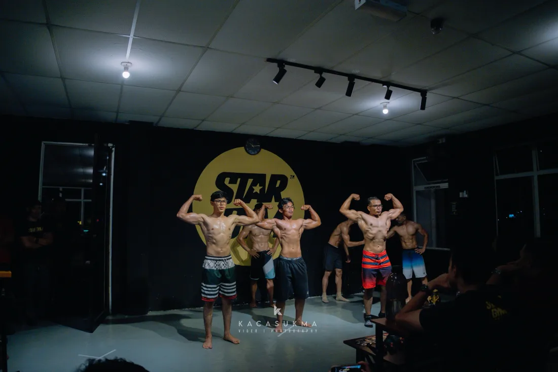 Athletes performing a back double biceps pose in lineup on stage